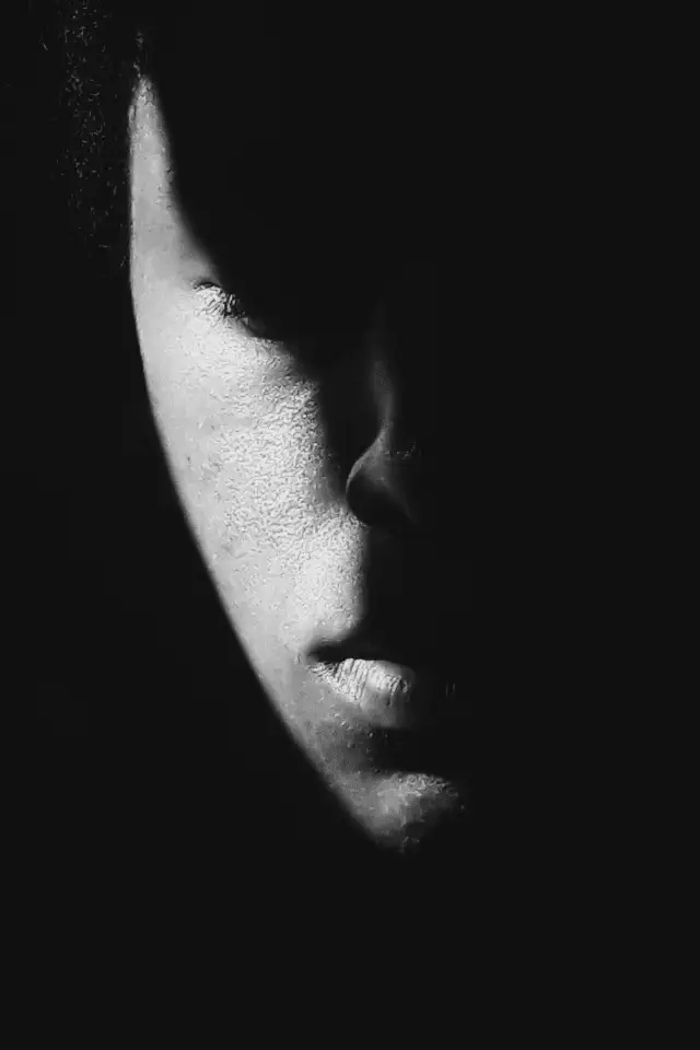 Primo piano di un volto in bianco e nero, metà immerso nell'ombra, simbolo della depressione e dell'isolamento interiore.