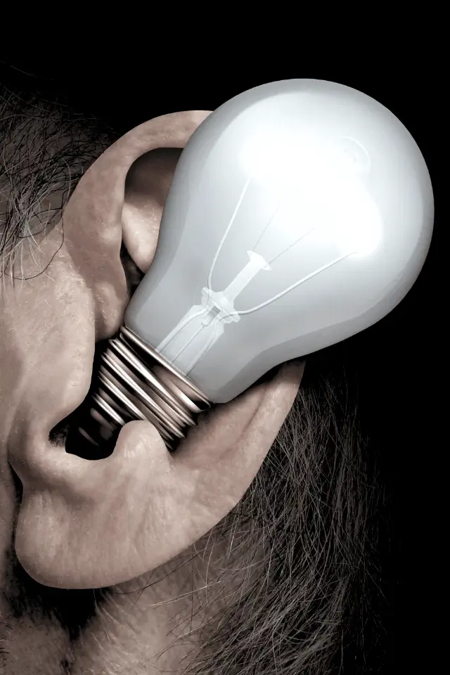 Lampadina nell’orecchio umano come metafora visiva dell’ascolto che genera comprensione e pace.