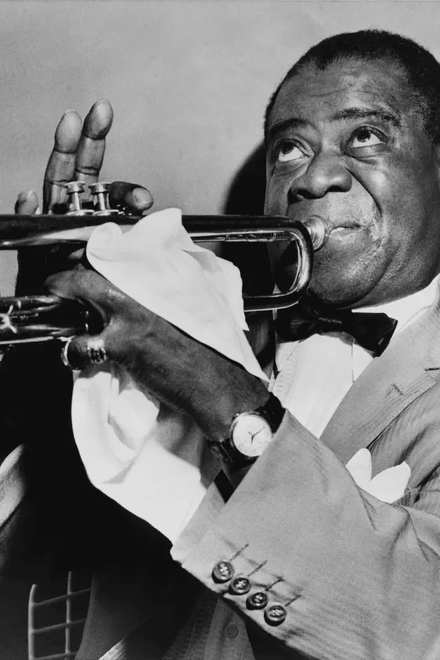 Louis Armstrong mentre suona la tromba, simbolo dell'arte di improvvisare nel jazz e nella vita.
