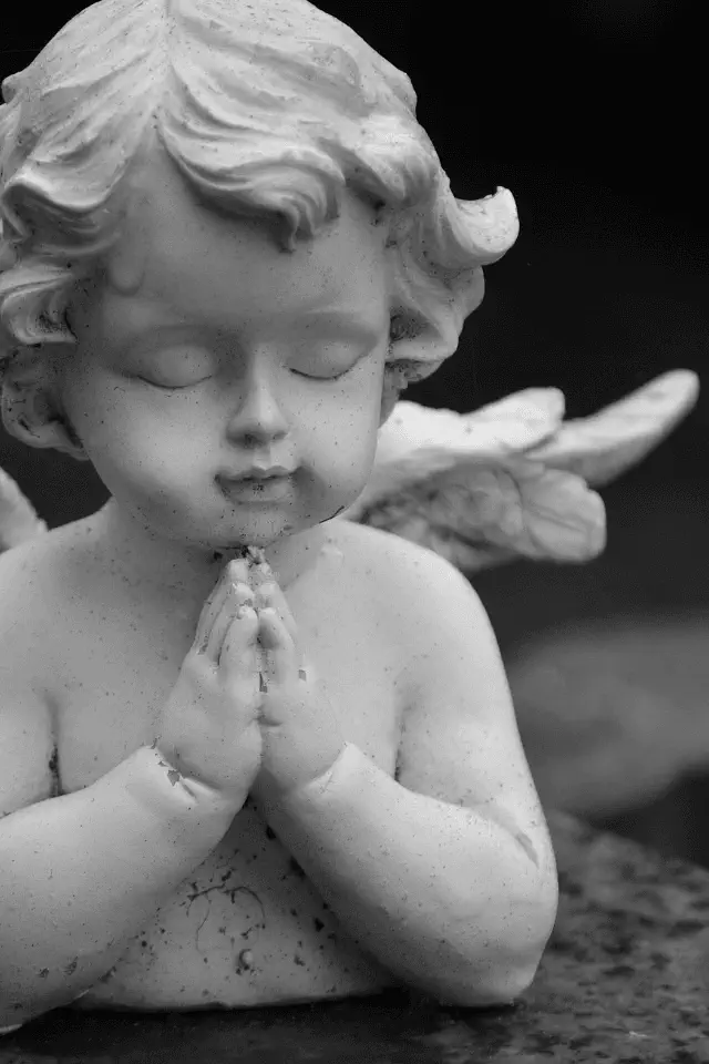 Statua di un angelo in preghiera con occhi chiusi, simbolo dell’innocenza e del desiderio di essere buoni.