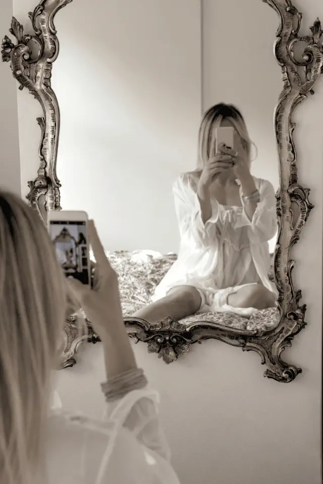 Donna che si fotografa allo specchio, simbolo del bisogno di essere visti e riconosciuti.