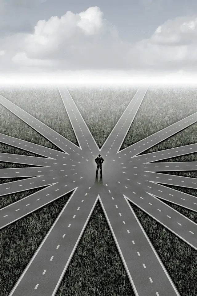 Una persona ferma al centro di molte strade che si diramano in direzioni diverse, simbolo della libertà di non scegliere.