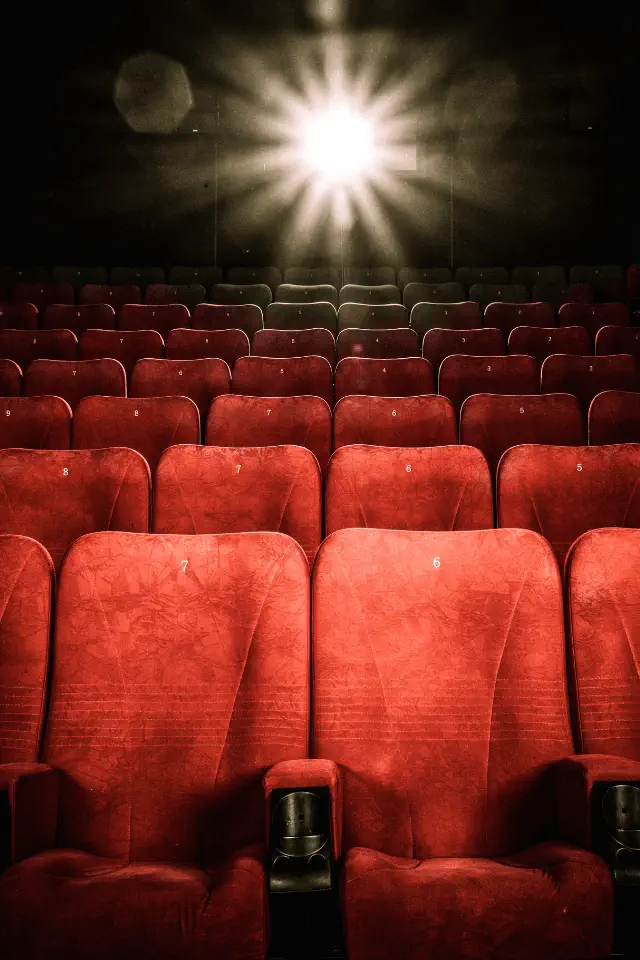 Sala di cinema vuota illuminata da un fascio di luce, simbolo della nostalgia di ciò che non abbiamo mai vissuto.